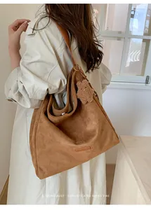 Detalle de un bolso hobo de ante marrón con un lindo colgante de oso en la correa