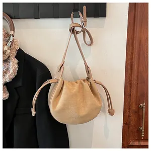Detaillierte Nahaufnahme der camel-wildleder Umhängetasche mit Tunnelzug und Mode-Logo-Prägung