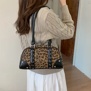 Sac Boston imprimé léopard avec clous et lanières en cuir noir porté par un modèle