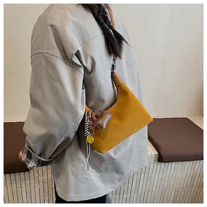 Detail of yellow faux suede bucket bag with leather strap and decorative charms