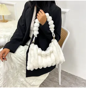 Détail d'un sac à main en peluche blanche avec boucles dorées et texture matelassée douce