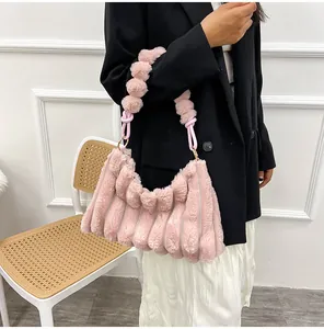 Détail du sac bandoulière en fausse fourrure rose avec rayures et nœud décoratif