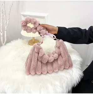 Détail d'un sac à main rose en fausse fourrure avec rayures et poignée à pompons