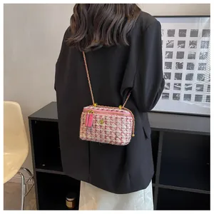 Détail du sac bandoulière en tweed avec chaîne et logo floral doré sur le modèle