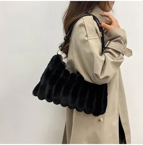 Détail d'un sac à épaule en peluche noire avec plis verticaux et anneaux en métal doré