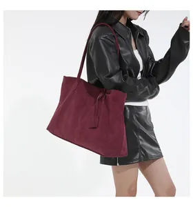 Detail of burgundy suede tote bag with fine shoulder strap on leather jacket outfit