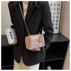 Dettaglio borsa a tracolla in tweed rosa con camelia dorata e tracolla a catena