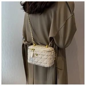 Dettaglio borsa a tracolla in tweed con camelia dorata su modella con cappotto kaki