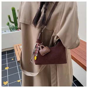 Detail of dark brown suede bucket bag with leather heart charm and smiley pendant