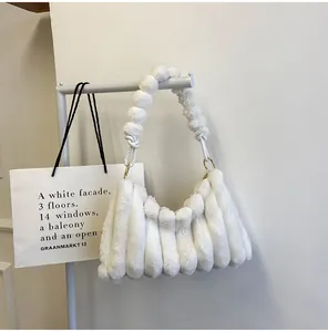 Vue détaillée du sac à main en fausse fourrure blanche avec pompon et anneaux métalliques