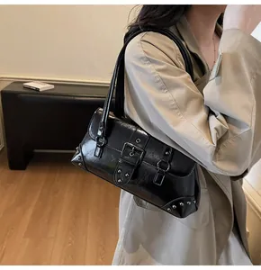 Détail du sac bandoulière en cuir noir brillant avec boucle argentée et rivets
