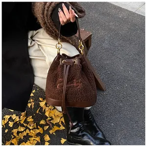 Close-up of brown plush bucket bag featuring embroidery and golden chain detail