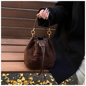Detailed view of brown shearling bucket bag with leather trim and gold metal hardware