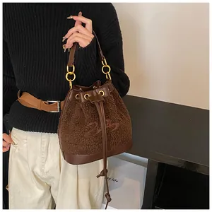 Detail of plush brown bucket bag with faux shearling texture and leather handle accents