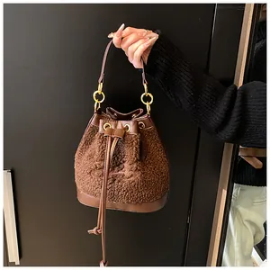 Detail of a brown plush bucket bag with drawstring closure and golden hardware handle
