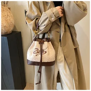 Detail of lamb wool leather bucket bag with contrast stitching and gold hardware on model