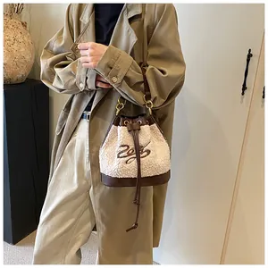 Detail of plush bucket bag with drawstring closure and brown leather trim on model