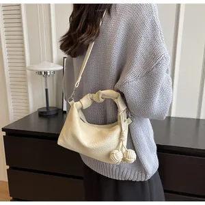 Off-white crossbody bag with pebble grain texture and decorative knotted handle on model