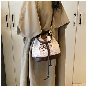 Detail of cream fleece bucket bag with brown leather drawstring and 2023 embroidery