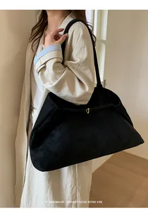 Close-up of black minimalist tote bag with golden buckle on a model in trench coat