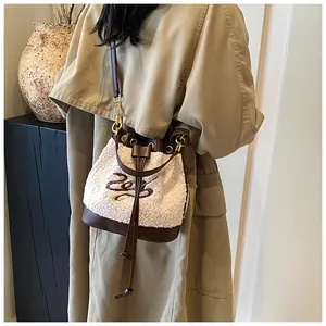 Detail of plush bucket bag with leather trim worn on a khaki coat for winter style