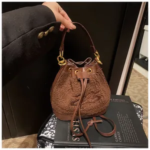 Detail of plush brown bucket bag with orbital embroidery and textured drawstring tassel