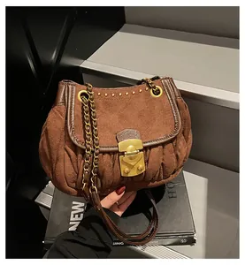 Close-up of vintage brown shoulder bag showing matte suede texture and gold chain strap