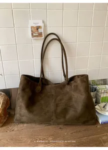 Close-up of deep brown tote bag showing smooth suede texture and decorative stitching
