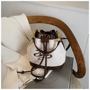 Detail of plush bucket bag featuring white fleece material and brown leather drawstring