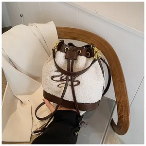 Detail of white shearling bucket bag with brown leather trim and logo embroidery