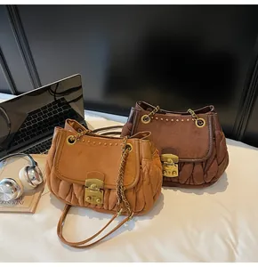 Detail of dark brown and camel suede pleated shoulder bags with metallic chain and clasp