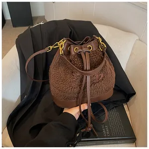 Detailed close-up of brown plush drawstring bucket bag with leather trim on a sofa
