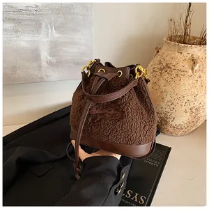 Detailed view of plush brown bucket bag with leather accents and gold hardware on black blazer