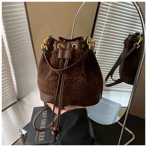 Detail of winter brown faux fur bucket bag with leather trim and gold hardware accents