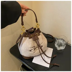 Detail of white plush and brown leather bucket bag with drawstrings and logo embroidery