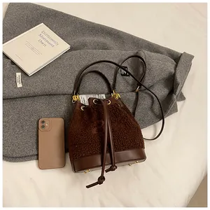 Detailed close-up of brown plush bucket bag with leather trim and gold chain handle