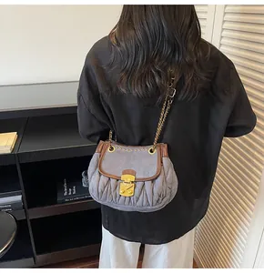 Détail du sac à chaîne matelassé bleu-gris avec bordure en cuir brun et rivets dorés