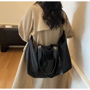 Detail of high-capacity black canvas tote bag with leather straps on a model