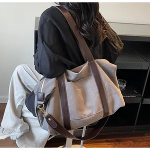 Detailed view of a large canvas tote bag with leather straps and golden metal hardware