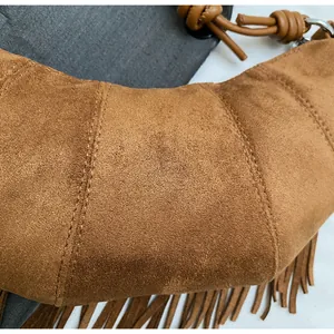 Detailed close-up of brown suede tassel handbag with intricate stitching and fringe trim
