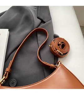 Detail of brown leather moon bag with detachable shoulder strap on office attire background