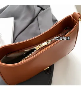 Detailed close-up of smooth golden metal zipper and dark fabric lining on brown bag