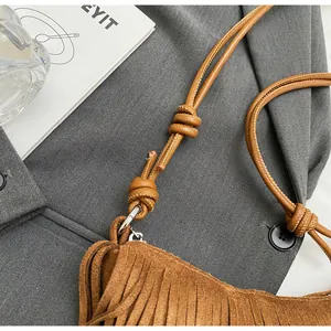 Close-up of brown suede bag with long tassels and adjustable knotted shoulder strap