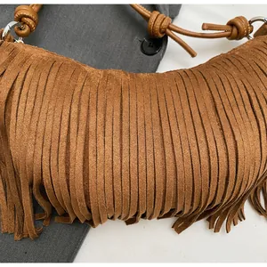 Detail of brown suede shoulder bag featuring tassel fringe and leather knot handle