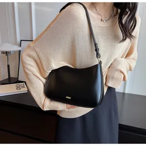 Detail of black leather hobo bag with gold metal logo and sleek adjustable strap
