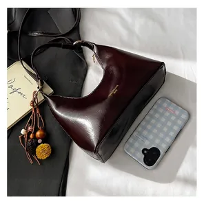 Detail view of burgundy faux leather shoulder bag with bohemian charm and gold logo