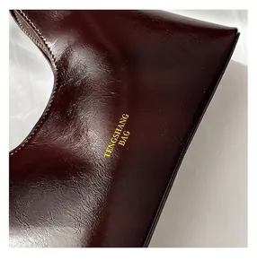 Close-up of wine red oil wax leather handbag showing fine texture and branded lettering