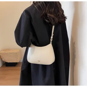 Detailed back view of a creamy off-white half-moon shoulder bag with gold logo on a model