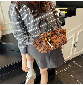 Detailed close-up of leopard print shoulder bag with brown round handle and beaded charm