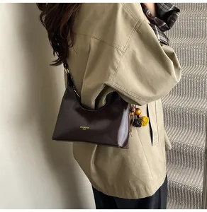 Detail van een donkerbruine hobo-tas van kunstleer met kwastje en goudkleurig logo